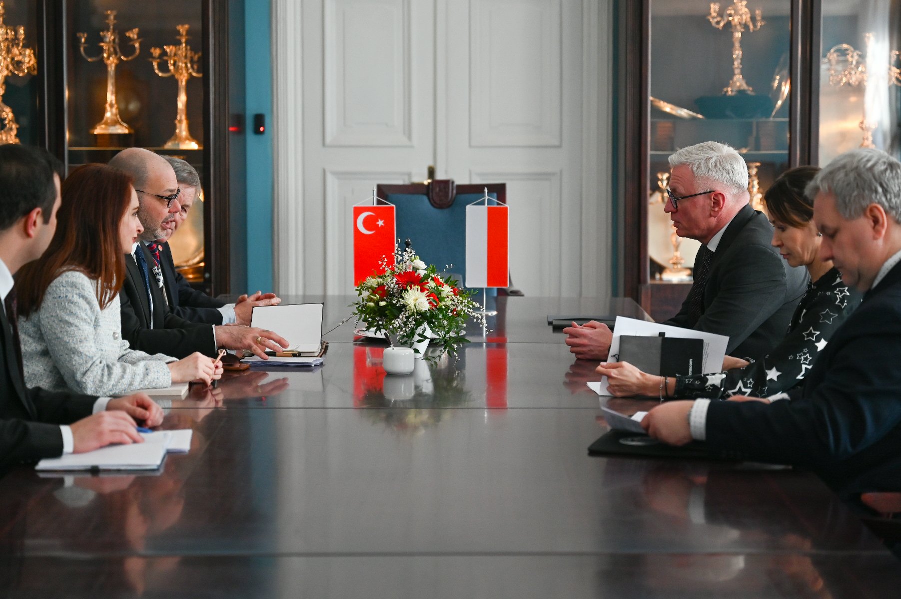 Na zdjęciu ludzie siedzący za stołem, na nim flagi Turcji i Polski - grafika artykułu