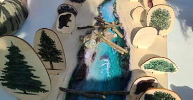 Plansza edukacyjna przedstawiająca rzekę, rośliny i zwierzęta nadrzeczne oraz żeremie i tamę